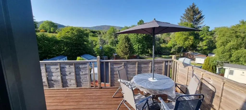 a patio with a table and an umbrella on a deck at Lynton lodges in Evanton