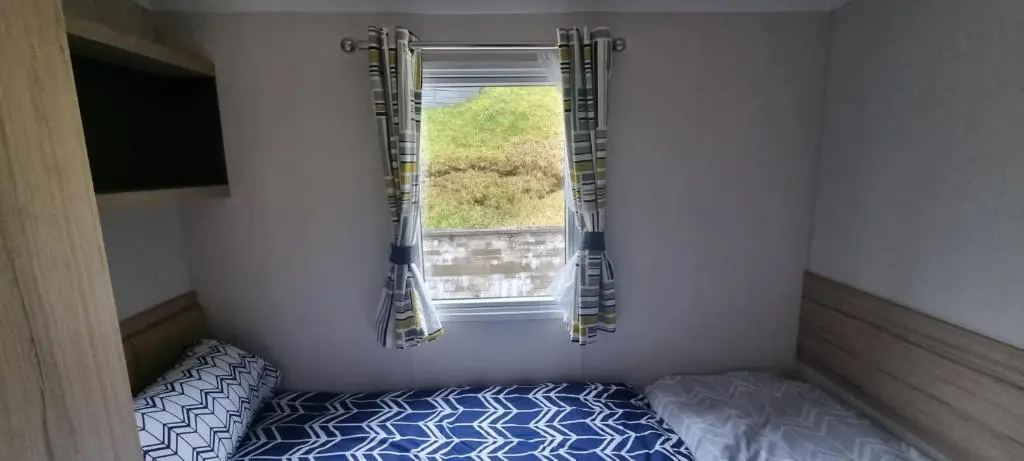 a small bedroom with a bed and a window at Lynton lodges in Evanton