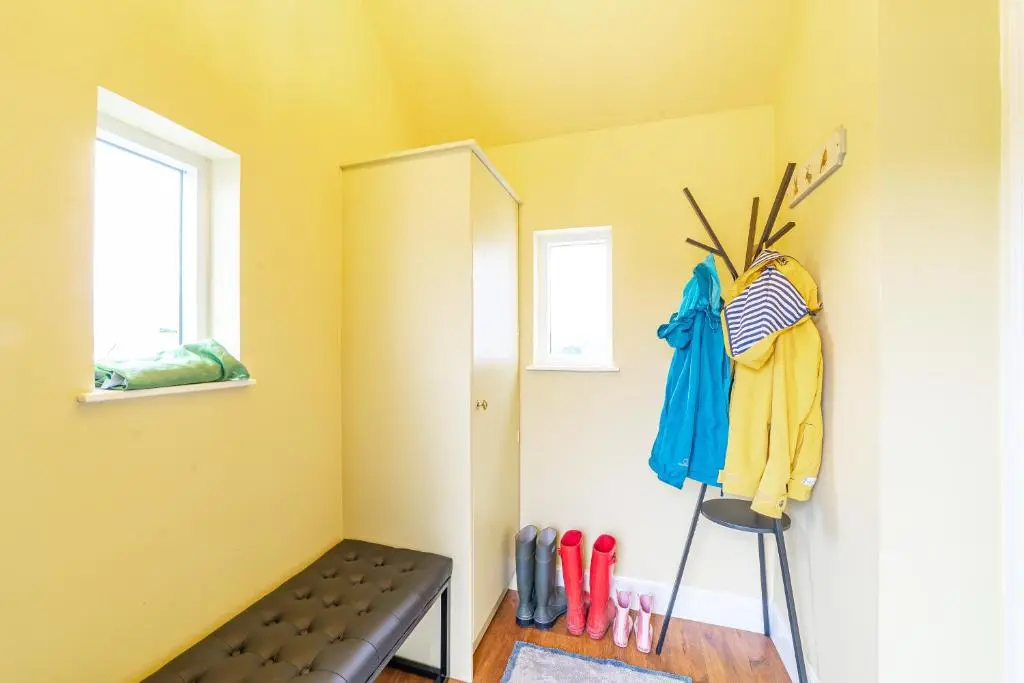 a room with a yellow wall with a shelf and clothes at Stags View with Hot Tub in Blairgowrie