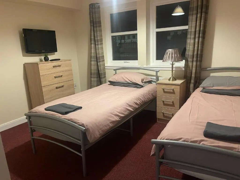 a bedroom with two beds and a television in it at Morlich Guesthouse in Dingwall