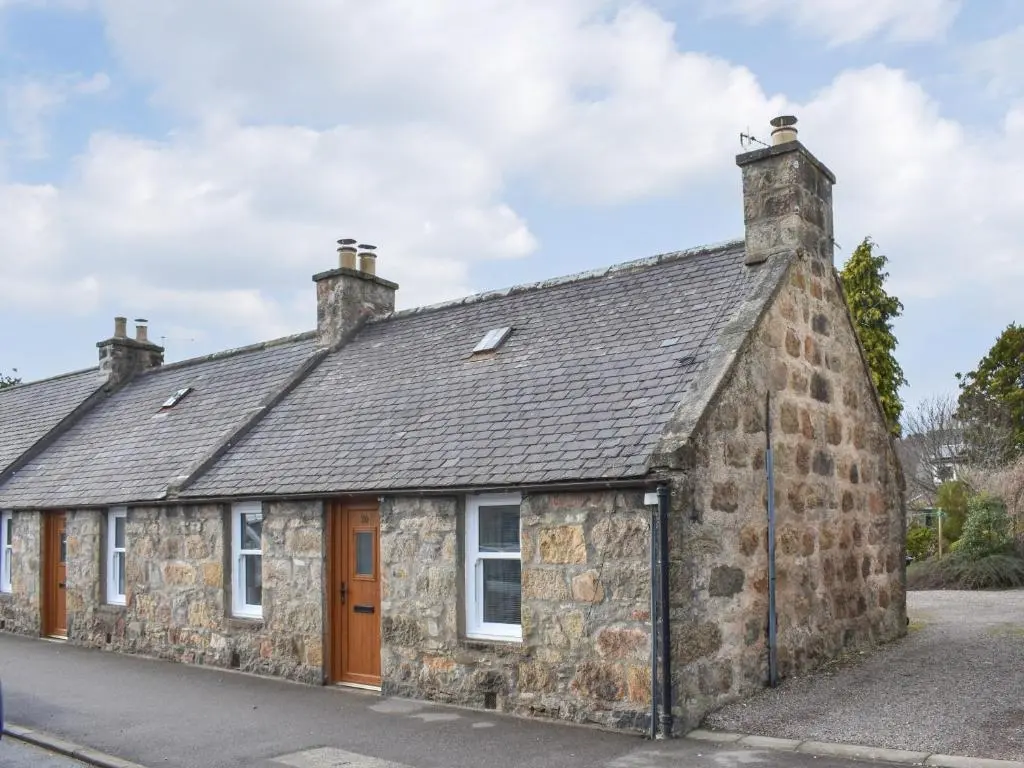 an old stone house on the side of a street at Rinnes Cottage in Aberlour