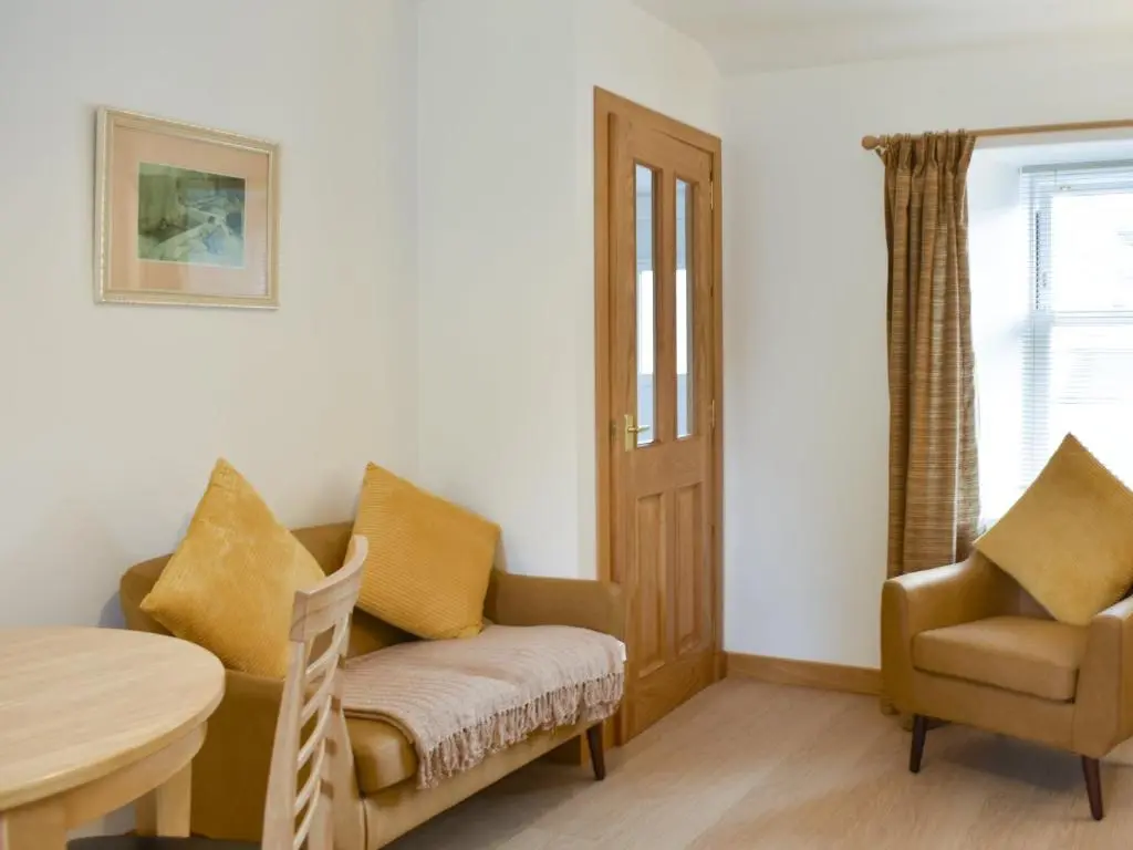 a living room with a chair and a table at Rinnes Cottage in Aberlour