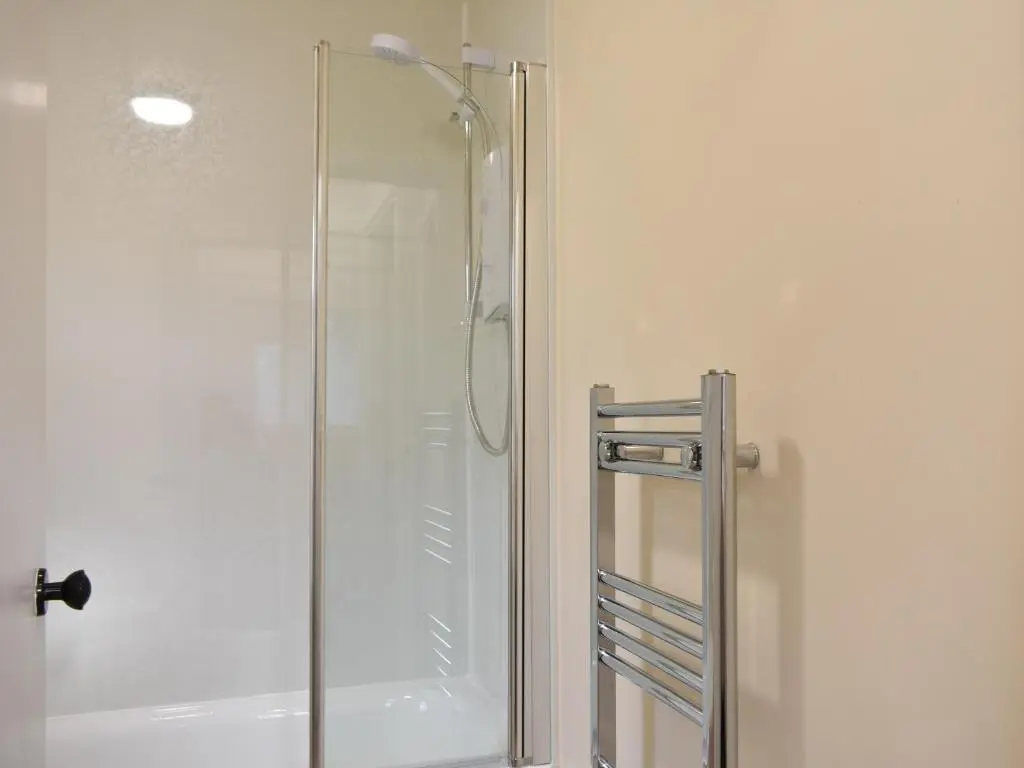 a shower with a glass door in a bathroom at Rinnes Cottage in Aberlour