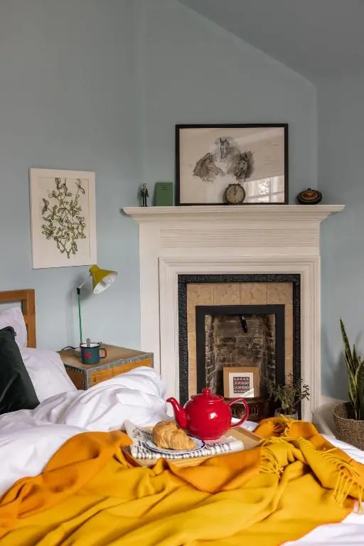 a bed with a teapot on a bed with a fireplace at North Lodge & River Cabin in Banchory