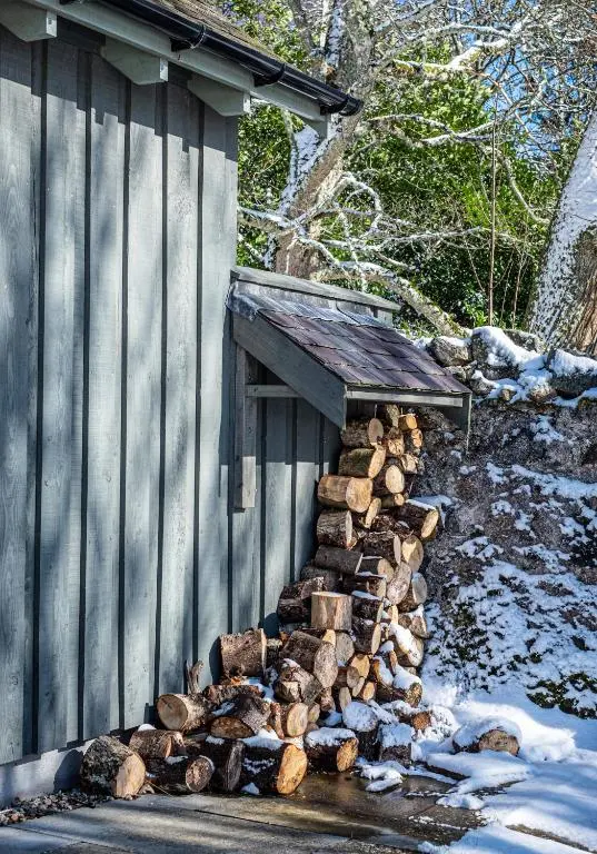 a pile of logs next to a building at The Kennels in Ballogie