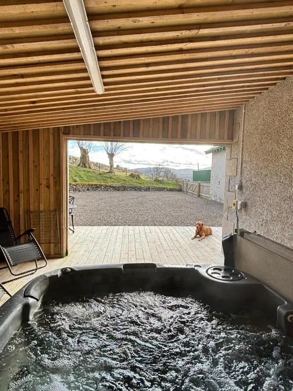 a hot tub in a house with a dog laying on the floor at The Stables with Hot Tub in Cray