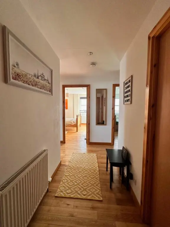 a hallway with a room with a table and a rug at City centre apartment next to Bus and Train Station in Inverness