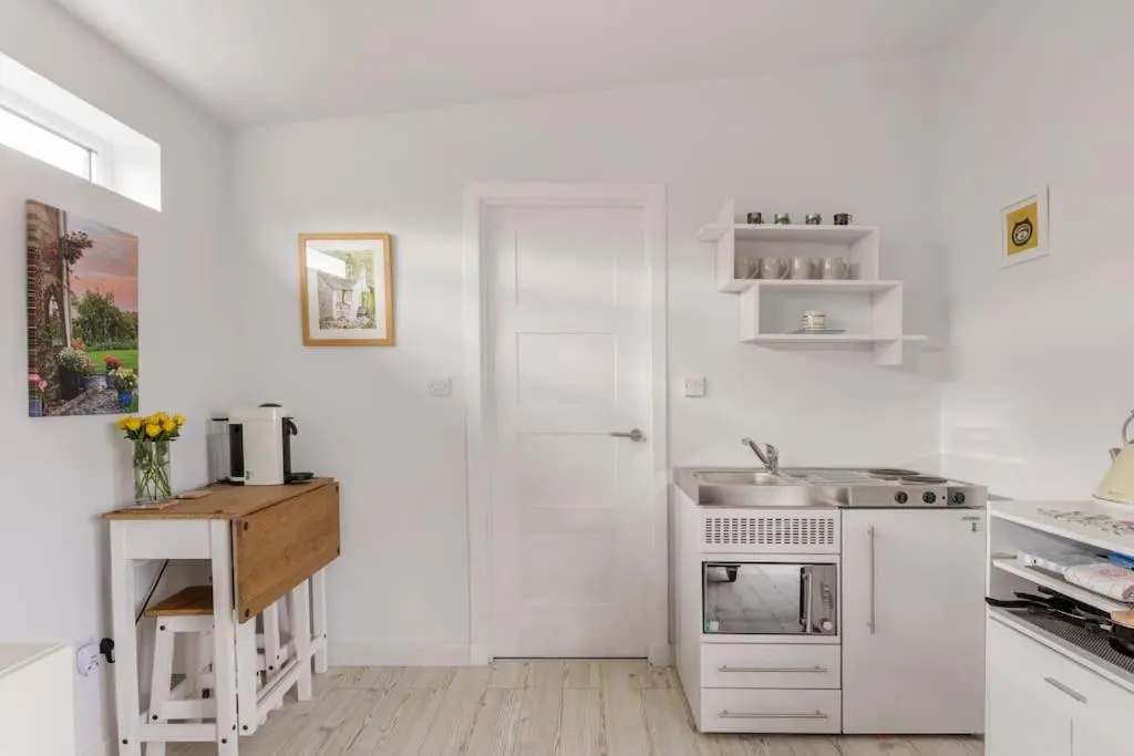a white kitchen with a sink and a stove at Cosy and modern 1 bedroom garden house - very dog friendly! in Tarves
