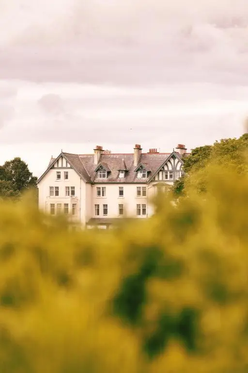 a large white house in the middle of a field at Dornoch Station in Dornoch