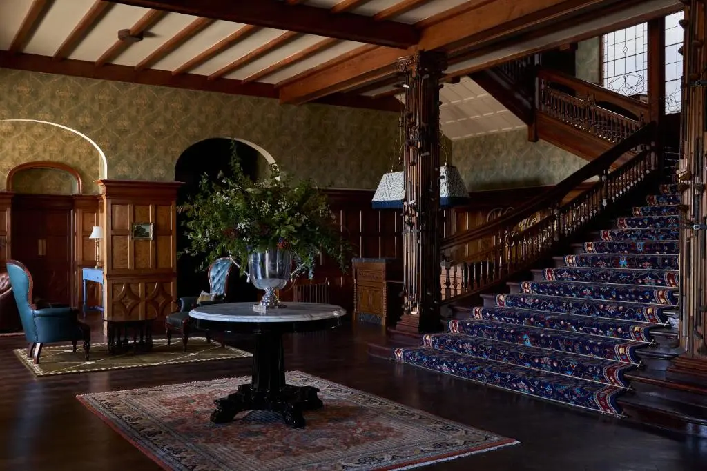 a room with a staircase and a table with a vase on it at Dornoch Station in Dornoch