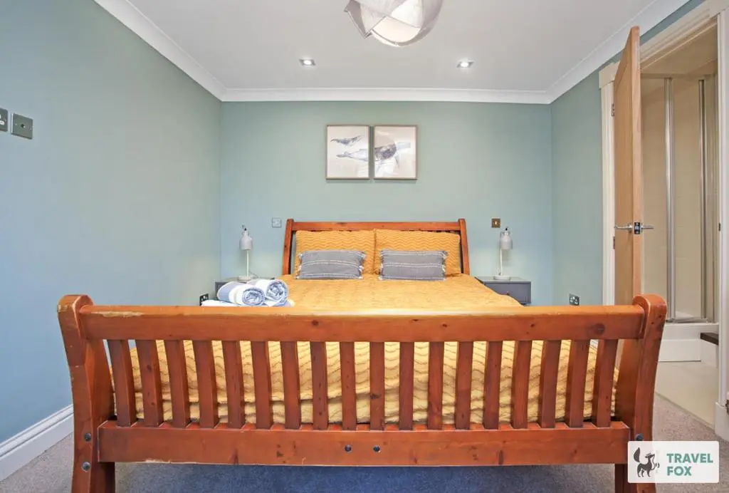 a bedroom with a wooden bed with blue walls at Daisy Cottage - Two bed country retreat with hot tub in Turriff