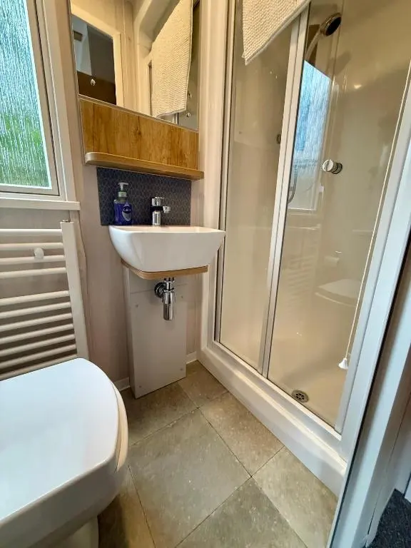 a bathroom with a shower and a toilet and a sink at The Telford Van - Beautiful, luxury static caravan in Aberlour