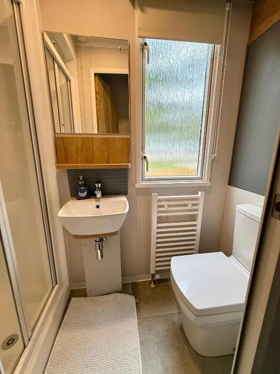 a small bathroom with a toilet and a sink at The Telford Van - Beautiful, luxury static caravan in Aberlour