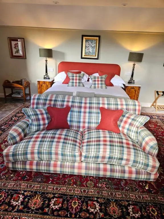 a large bed with a plaid couch in a room at Craggan in Ballater