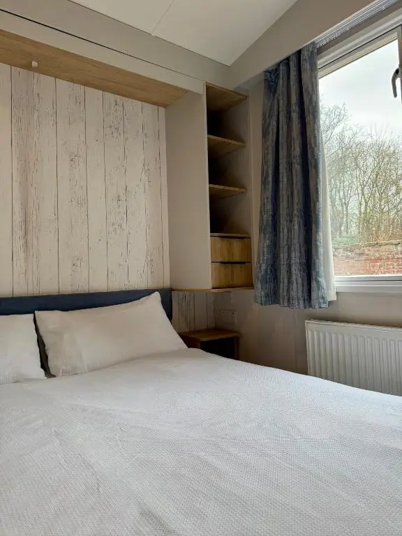 a bedroom with a white bed and a window at The Springer Van - Beautiful, luxury static caravan in Aberlour