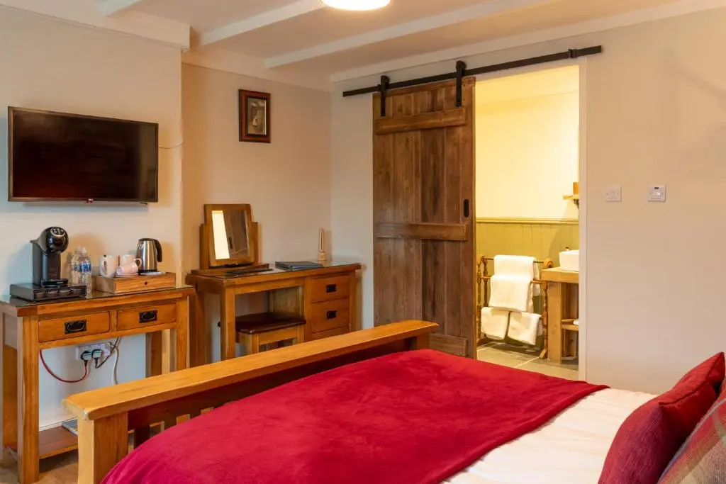 a bedroom with a bed and a tv on the wall at Bridgend House B&B in Drumnadrochit