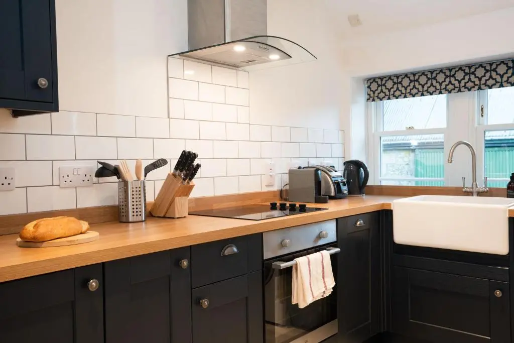 a kitchen with black cabinets and a sink at West Lodge - Seasgair Lodges in Kincraig