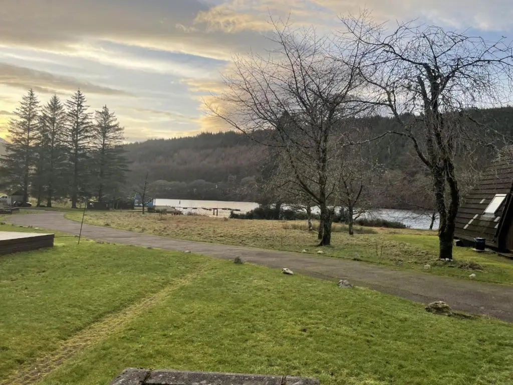 a road in a park with a river and trees at Caledonia Lodge in Spean Bridge