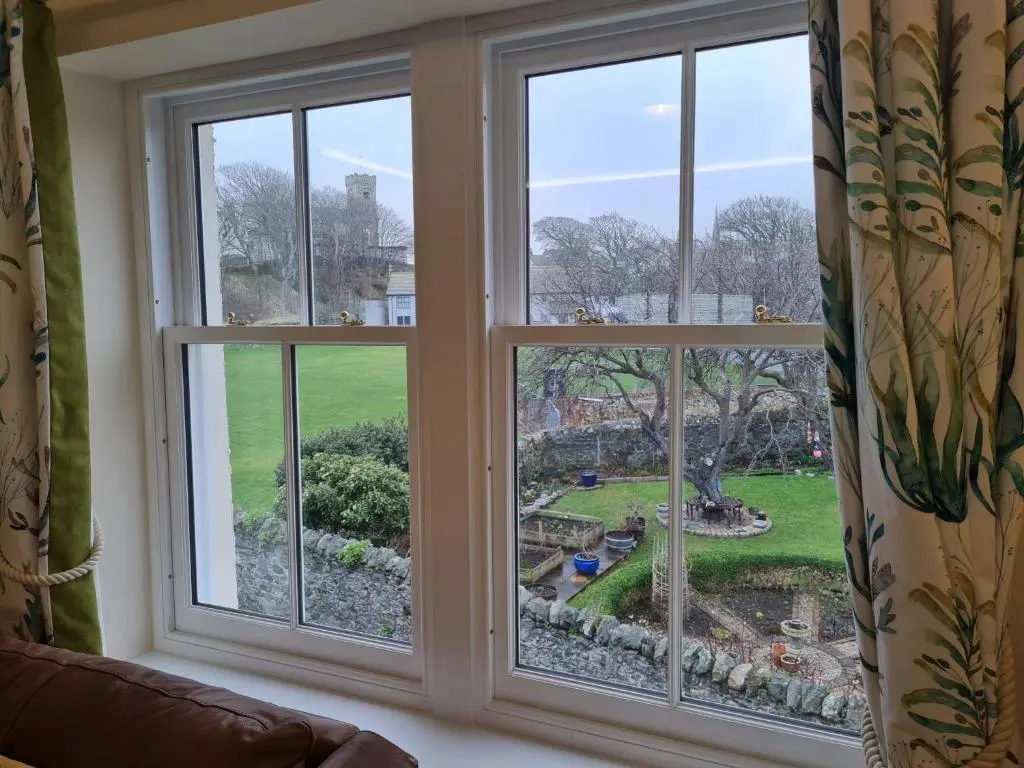 a room with three windows looking out at a garden at Old Police Station, Portsoy in Portsoy