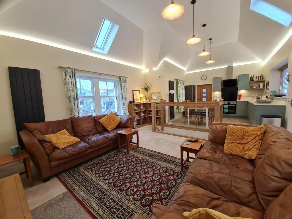 a living room with two couches and a kitchen at Old Police Station, Portsoy in Portsoy