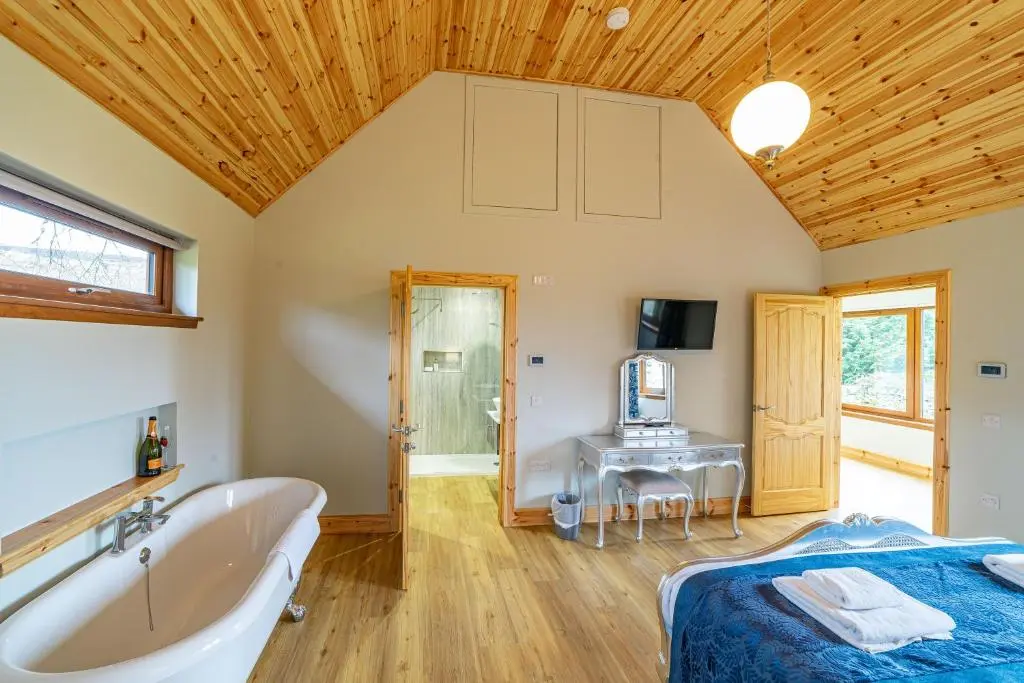 a bedroom with a tub and a bed and a desk at Roe Deer Lodge with Hot Tub in Cray