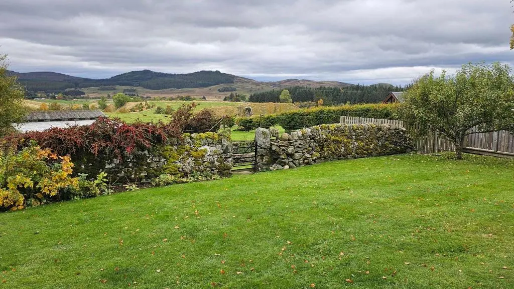 a yard with a fence and a stone wall at Roe Deer Lodge with Hot Tub in Cray