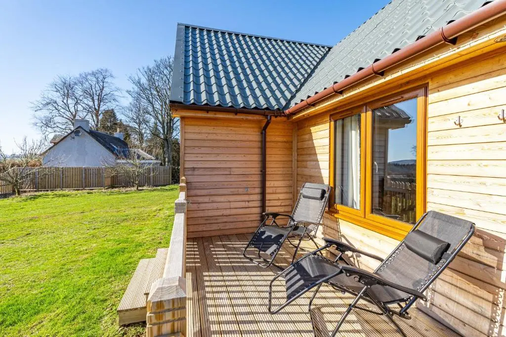 a couple of chairs sitting on a deck next to a house at Roe Deer Lodge with Hot Tub in Cray