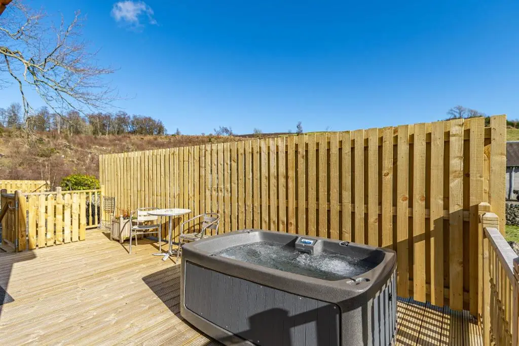 a hot tub on a deck with a wooden fence at Roe Deer Lodge with Hot Tub in Cray