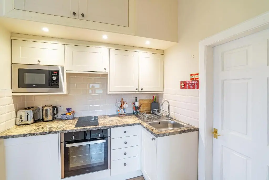 a kitchen with white cabinets and a sink and a microwave at Pine Marten Lodge with Hot Tub in Cray