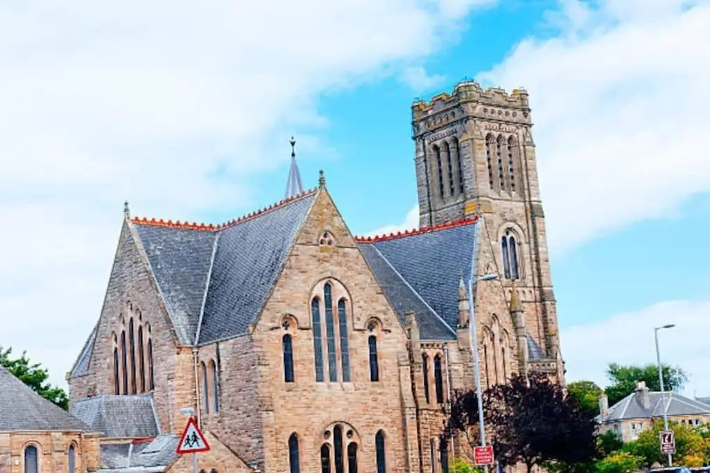a large brick church with a clock tower at The Apartment in Nairn