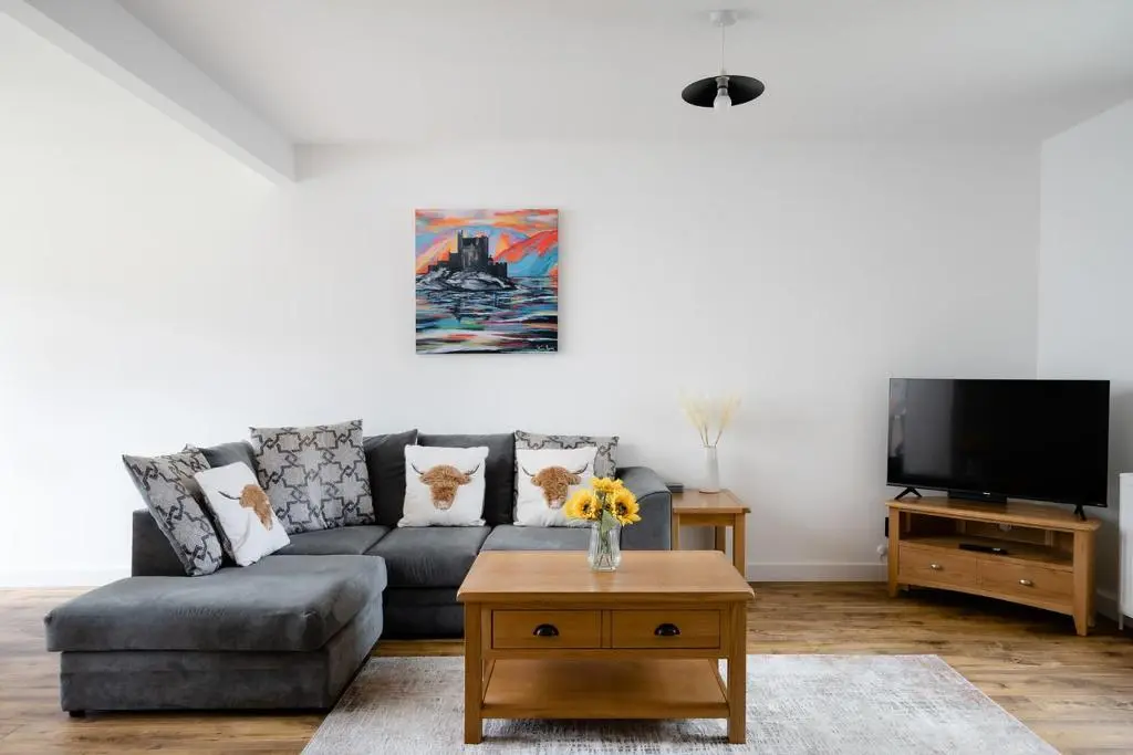 a living room with a couch and a tv at Ness Riverfront Holiday Home - City Centre in Inverness