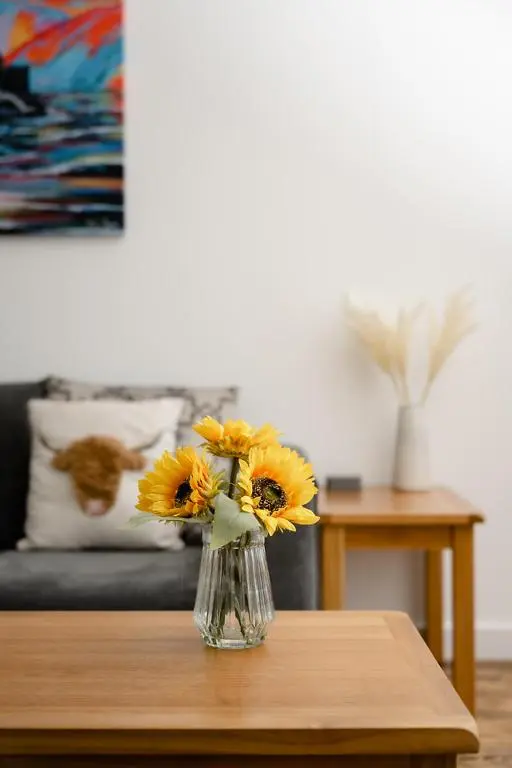a vase of yellow flowers sitting on a table at Ness Riverfront Holiday Home - City Centre in Inverness