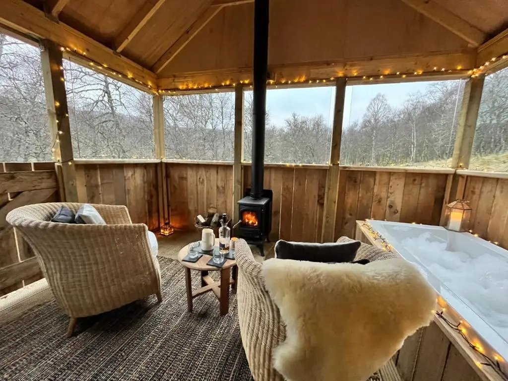 a room with a tub and chairs and a fireplace at The Dell at Glenlivet in Glenlivet