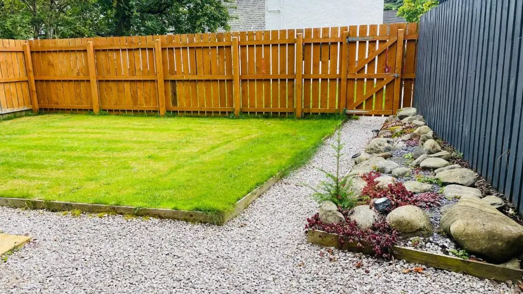a backyard with a fence and a yard with grass at Loch Ness Hideaway Pod in Lewiston