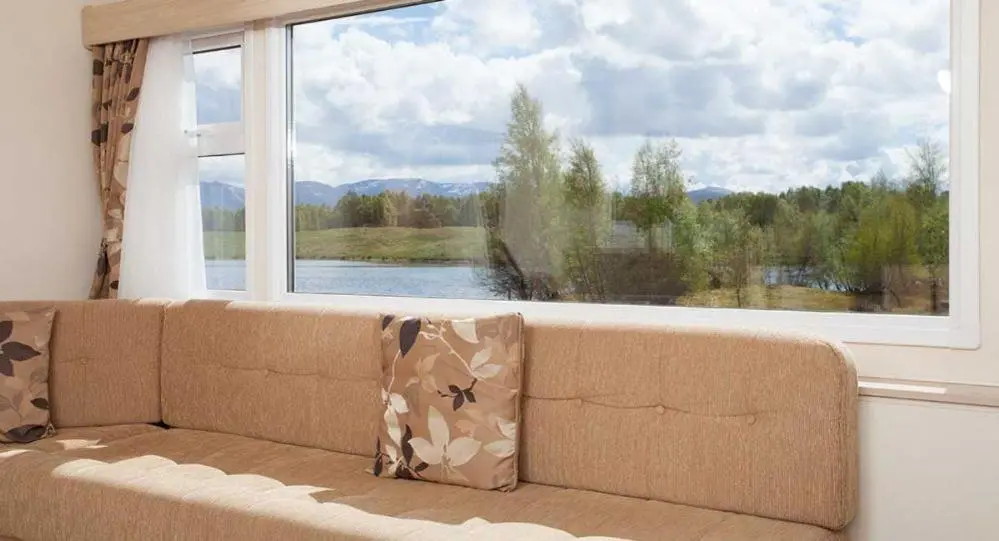 a couch sitting in front of a large window at The Hide near Aviemore in Aviemore