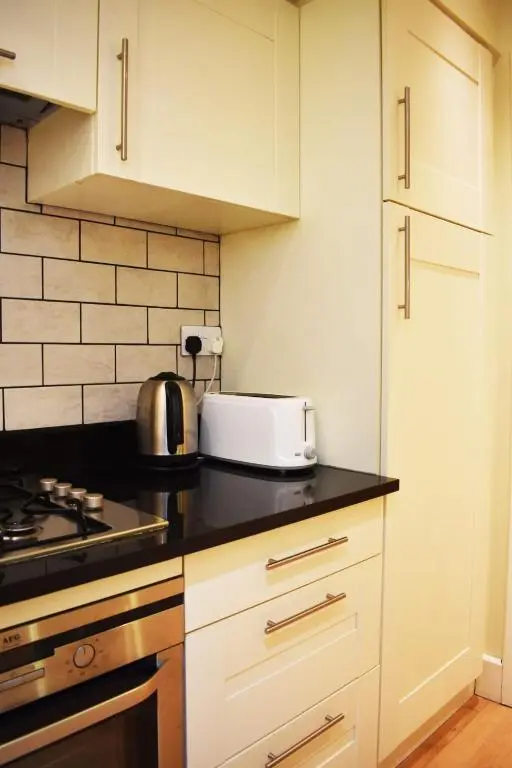 a kitchen with white cabinets and a toaster on a counter at The Ross 2 bedroom apartment in historic Abbey in Fort Augustus