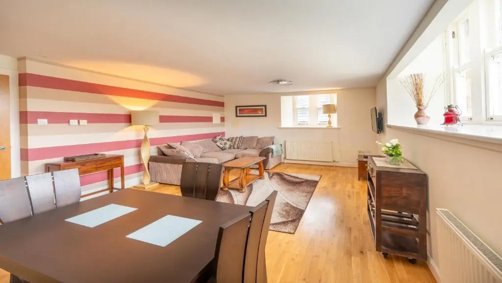 a living room with a table and a couch at Monastery apartment with Loch Ness view in Fort Augustus