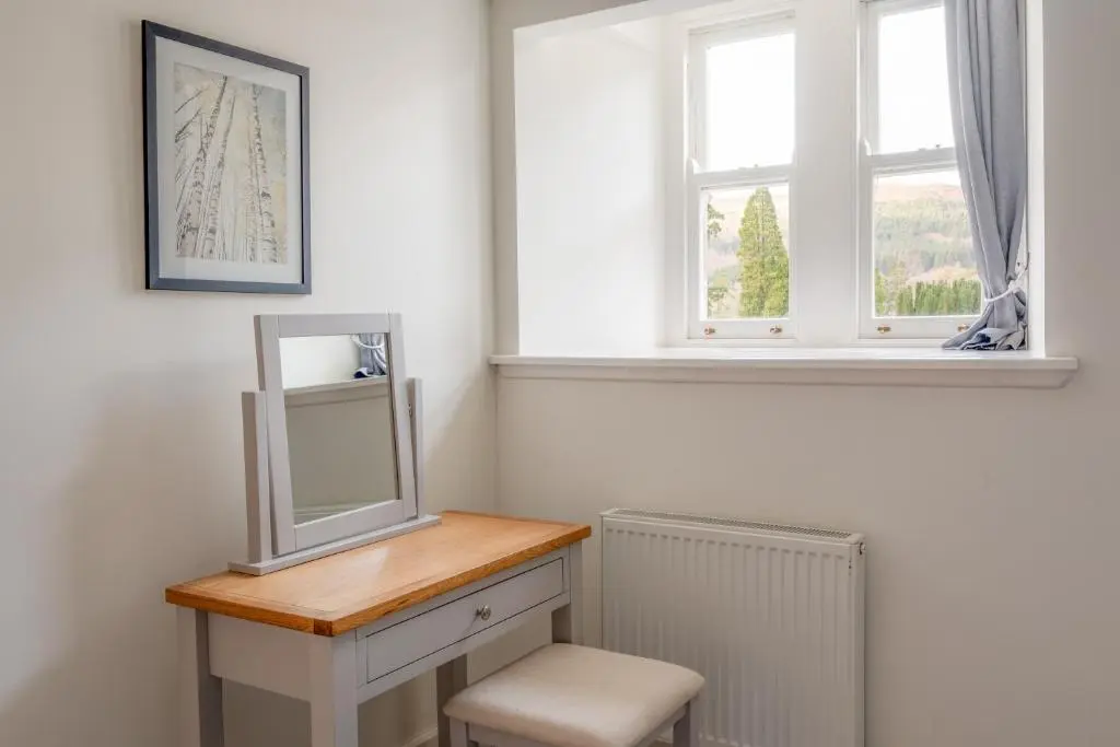 a bathroom with a mirror and a stool and a window at Monastery apartment with Loch Ness view in Fort Augustus