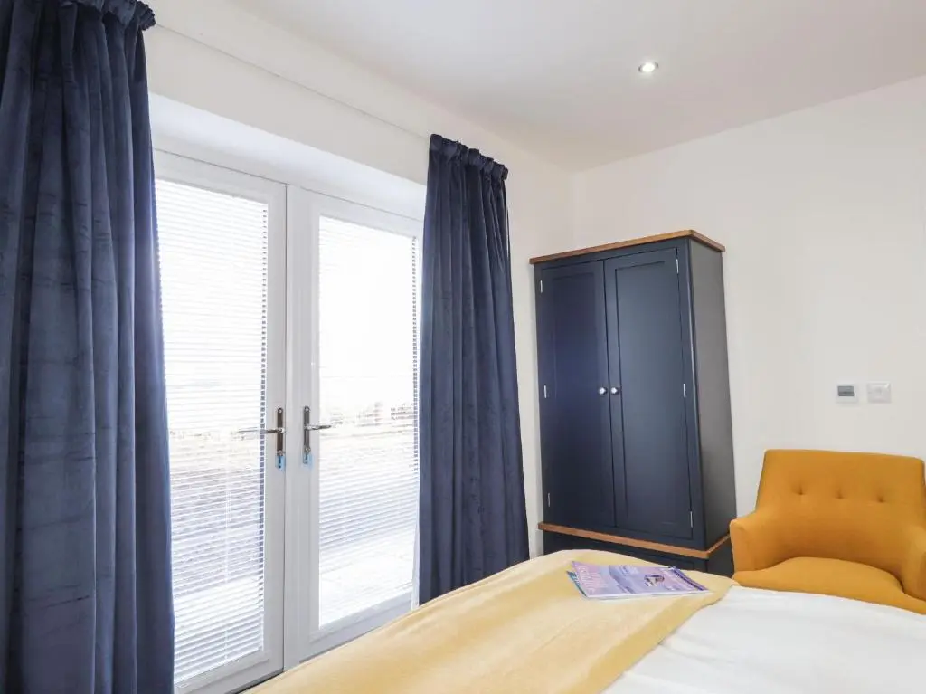 a bedroom with a bed and a cabinet and a window at Firthview in Nairn