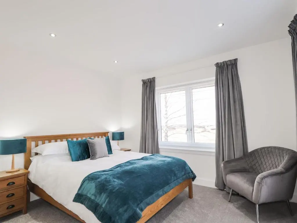 a bedroom with a bed and a chair and a window at Firthview in Nairn