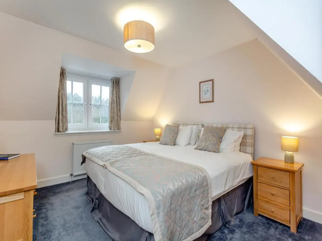 a bedroom with a bed and a desk and a window at Cruives Lodge in Kiltarlty