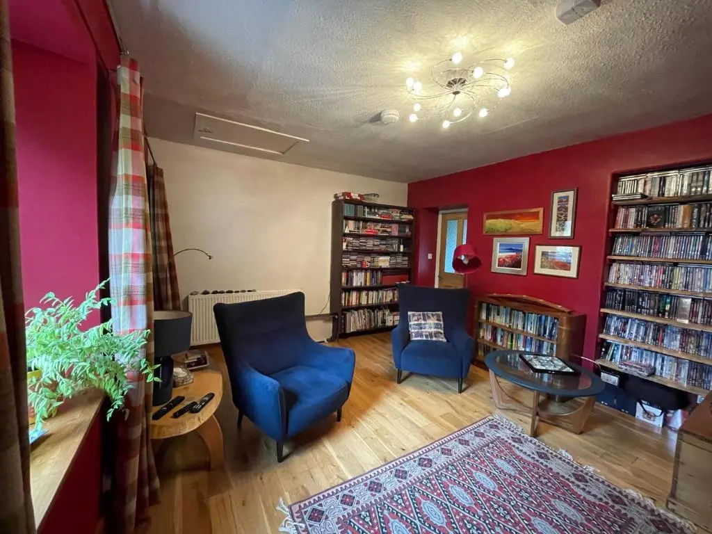 a living room with two blue chairs and a red wall at One bed cosy Highland cottage near Beauly in Beauly