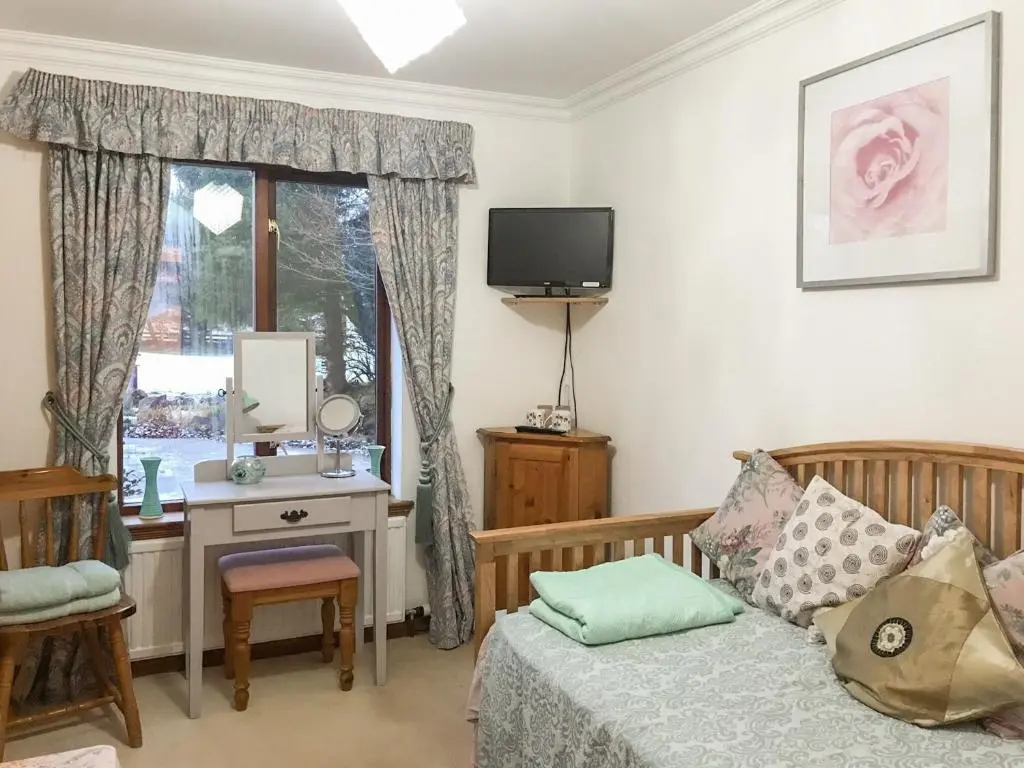 a bedroom with a bed and a desk and a television at Scardroy Alford in Alford