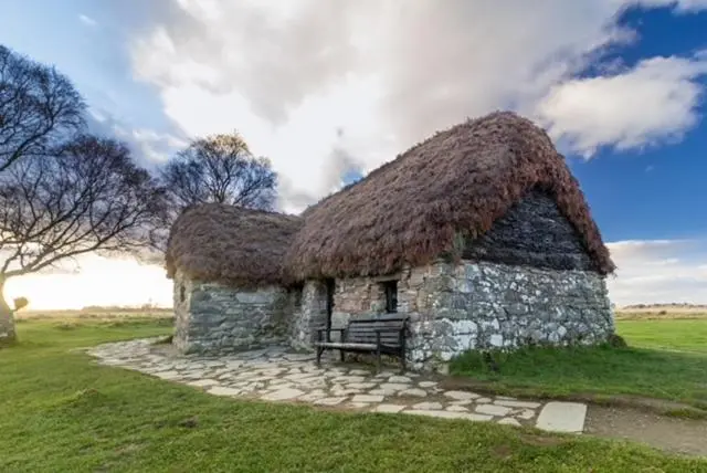 a stone building with a grass roof with a bench in front at The Roost in Aviemore
