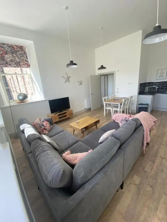 a large couch in a living room with a table at Hiltula spacious premium apartment with beautiful views in Inverness