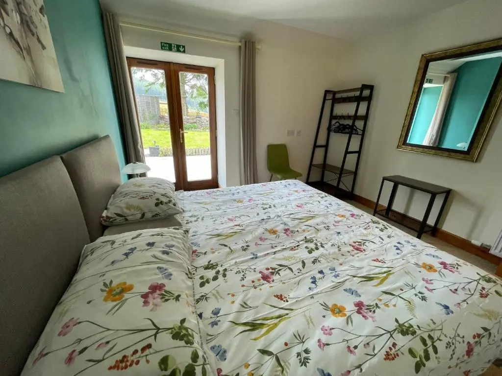 a bed with a floral comforter in a bedroom at Barclay\u2019s But n Ben in Alford