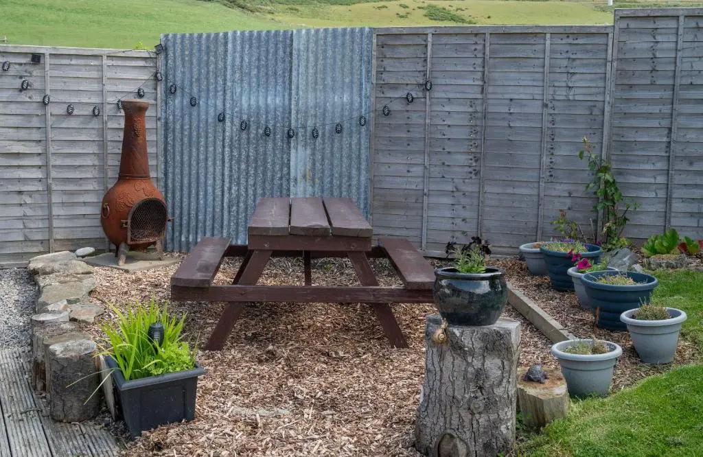 a wooden picnic table and bench in a garden at Barclay\u2019s But n Ben in Alford