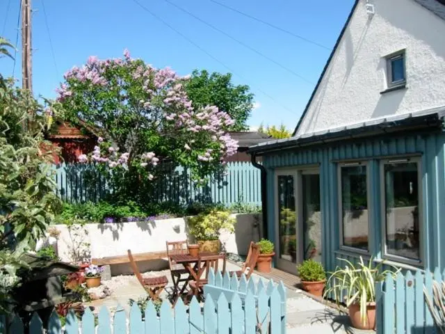 a house with a fence and a wooden table and bench at Driftwood Cottage, Findhorn Village in Forres