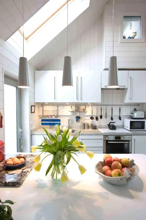 a kitchen with a bowl of fruit on a table at Driftwood Cottage, Findhorn Village in Forres