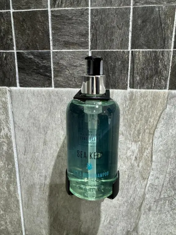 a green bottle of soap sitting on a tile wall at Central 2 bedroom apartment in Wick